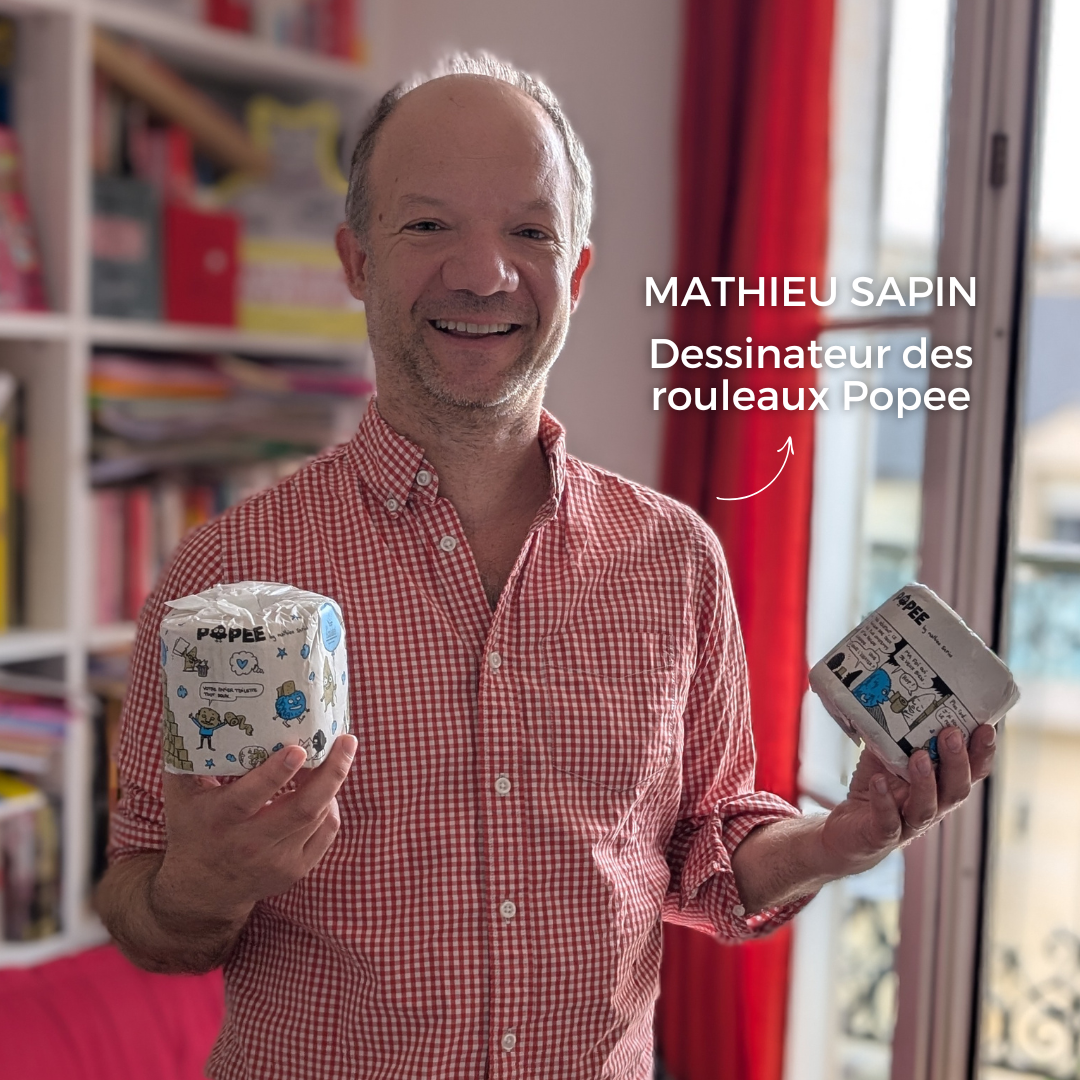 Mathieu Sapin, illustrateur et auteur, tenant les rouleaux de papier toilette Popee qu’il a dessinés.