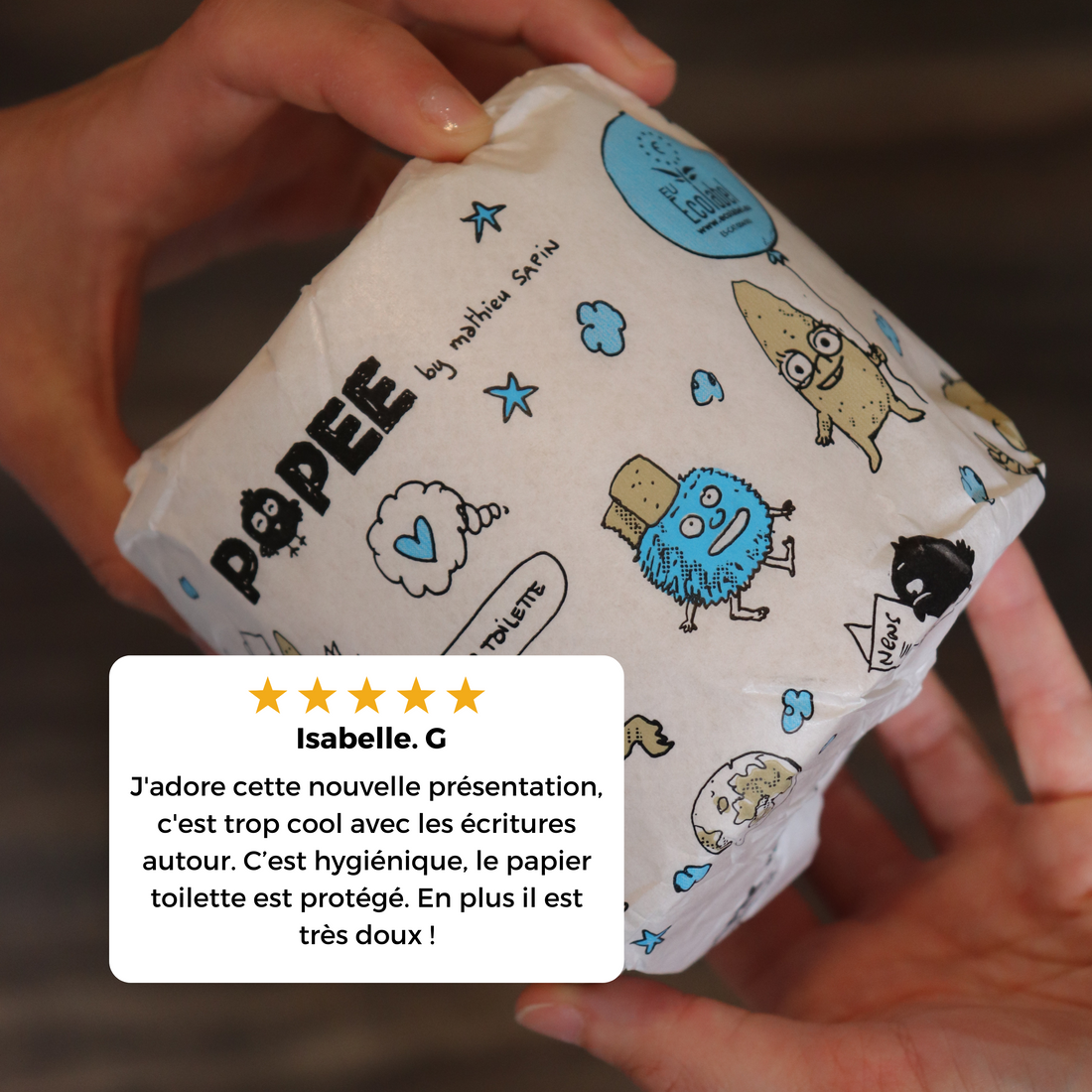 Papier toilette Popee x Mathieu Sapin tenu en main, avec avis client soulignant l’emballage hygiénique et la douceur.