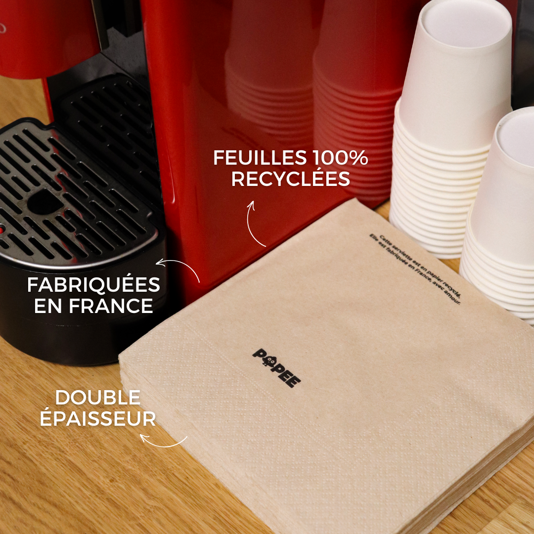 Serviettes recyclées Popee posées près d’une machine à café, étiquettes double épaisseur et made in France.