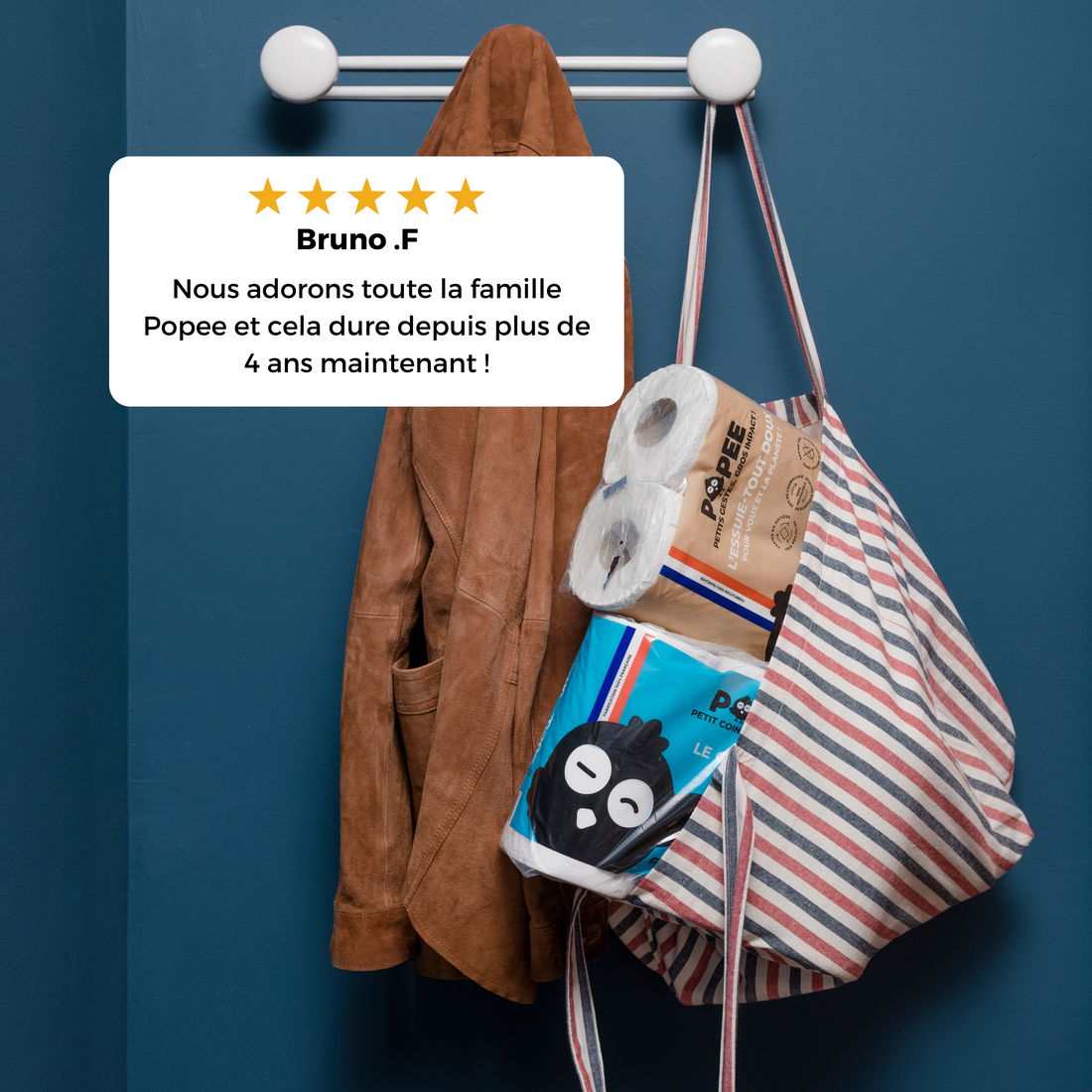 Un sac rayé contenant des rouleaux Popee suspendu à une patère, avec l’avis client de Bruno affiché.