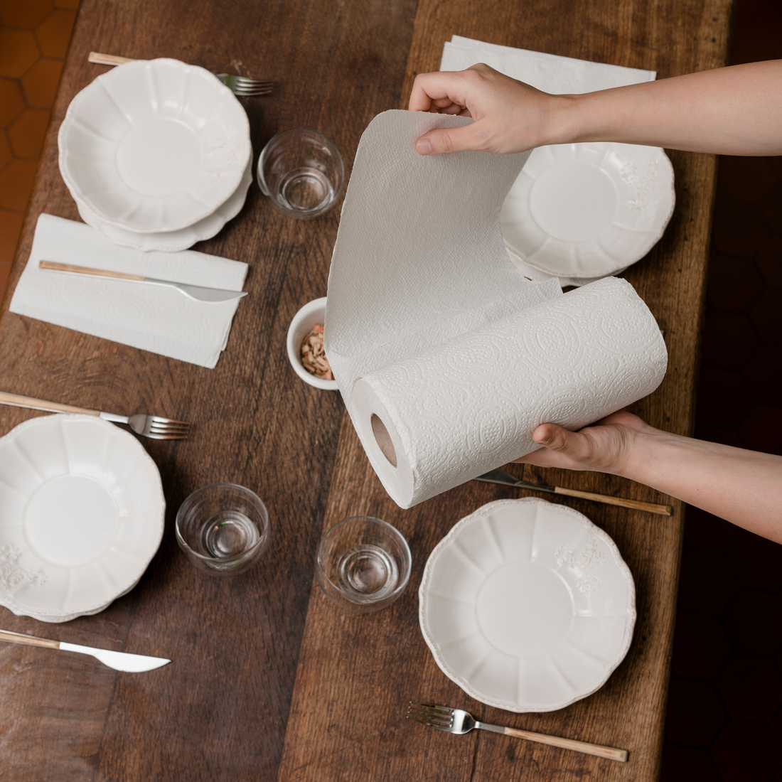 Une personne détache une feuille d’essuie-tout Popee au-dessus d’une table dressée, ambiance conviviale et écoresponsable.