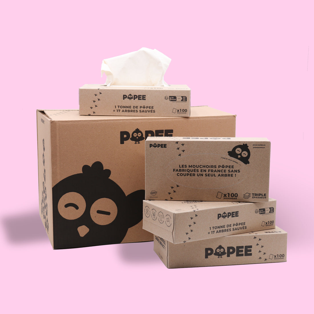 Pack de boîtes de mouchoirs recyclés Popee empilés sur carton d’expédition, fond rose.